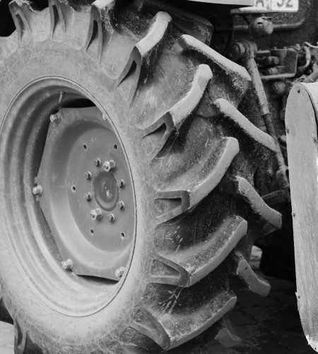 Grayscale photograph highlighting detailed tractor wheel design.